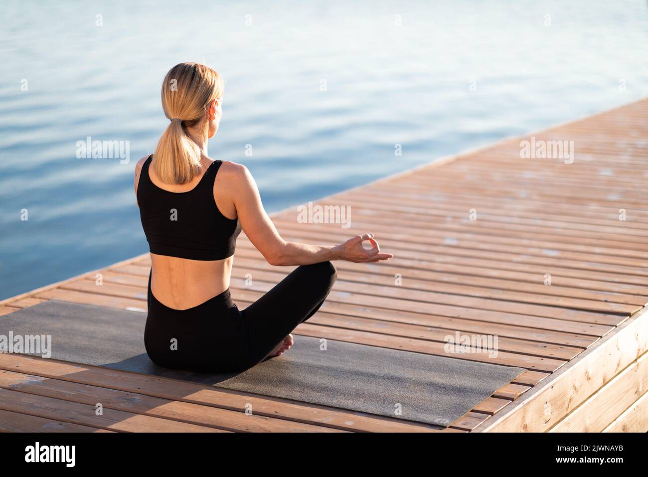 Morning Meditation. Calm Blond Woman Practicing Yoga Outdoors, Meditating In Lotus Position Stock Photo