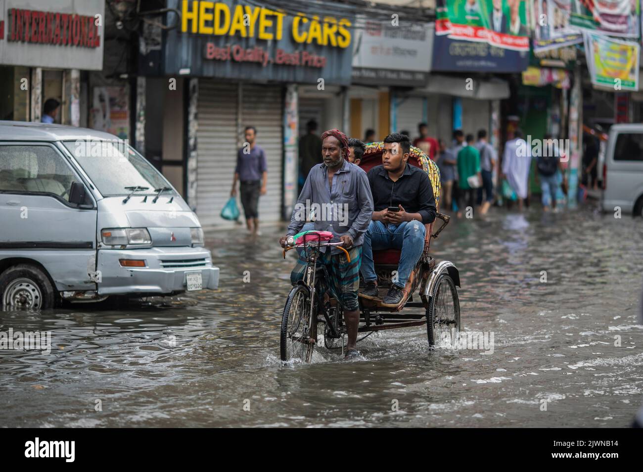 A rickshaw drives a passenger through the waterlogged streets of Dhaka ...