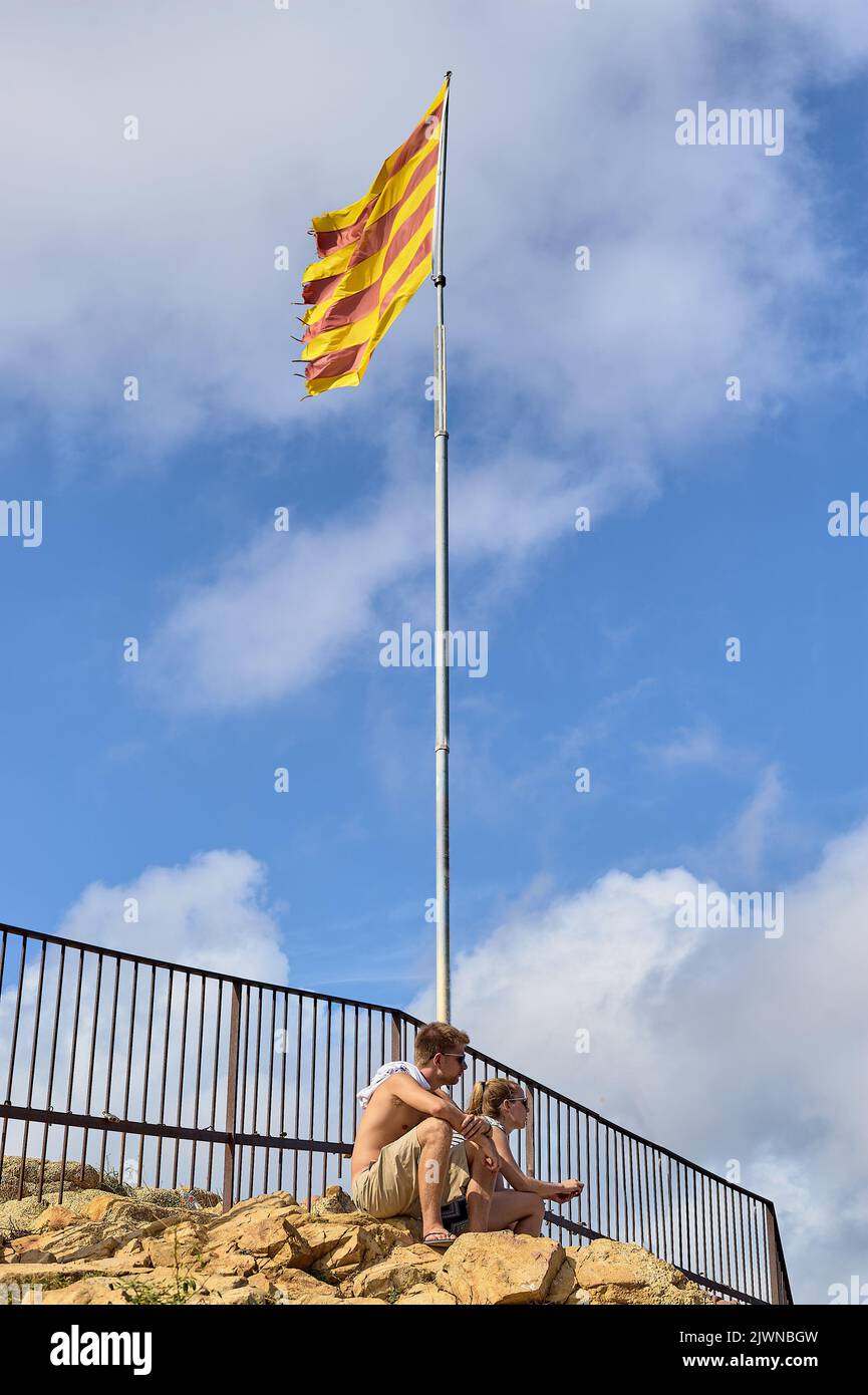 Blanes, Catalonia, Spain September 4 2022: Young couple sitting under the flag of Catalonia in the concept of the celebration of the day of September Stock Photo