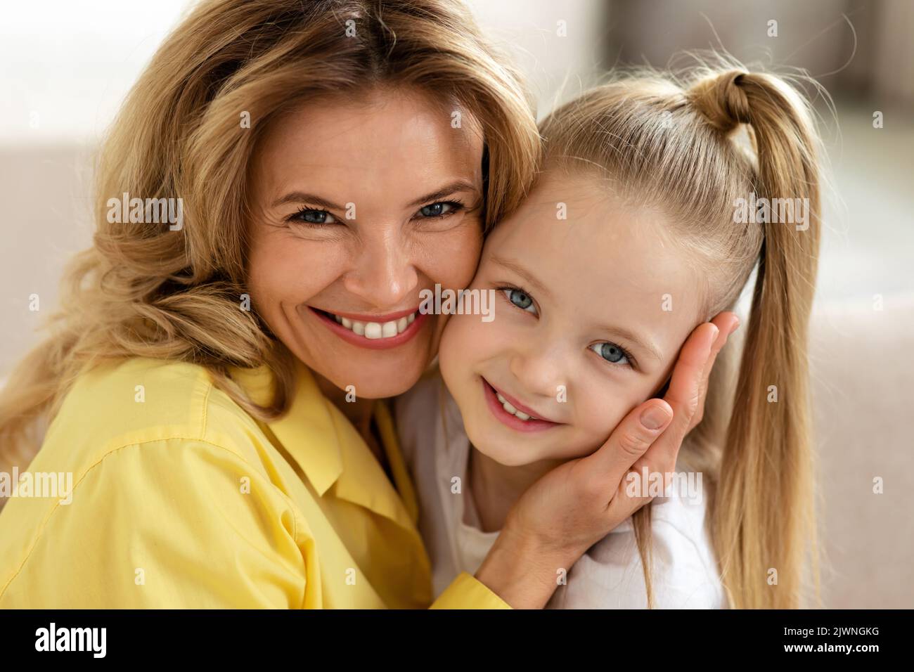 Portrait Of Middle Aged Mother And Little Daughter Embracing Indoor Stock Photo