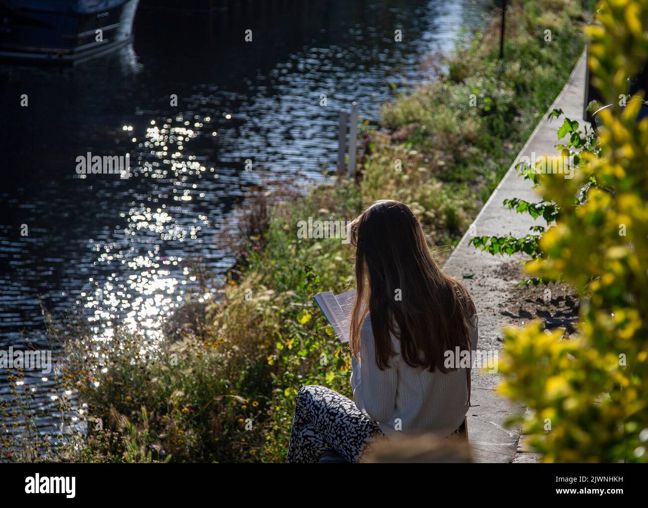 Young girl reading beside an Amsterdam canal Stock Photo