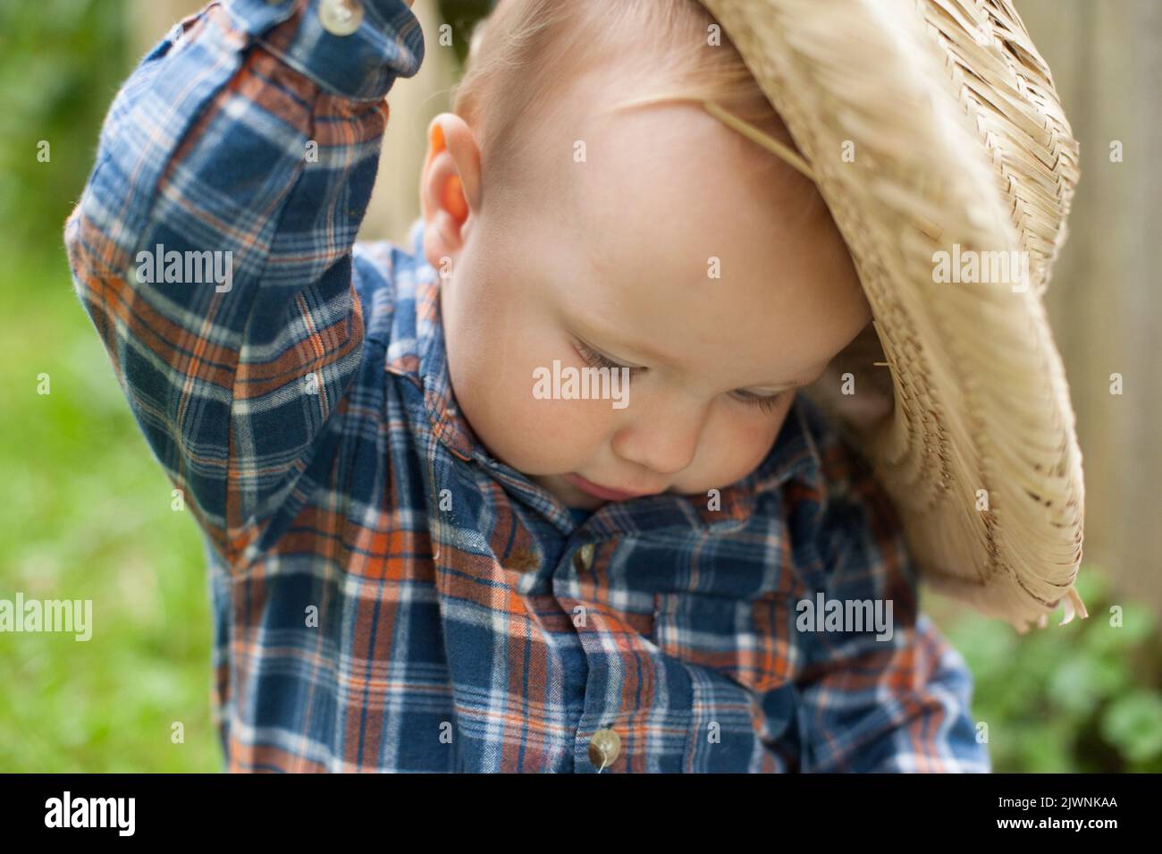 A portrait of a toddler in a plaid shirt and straw hat. Stock Photo