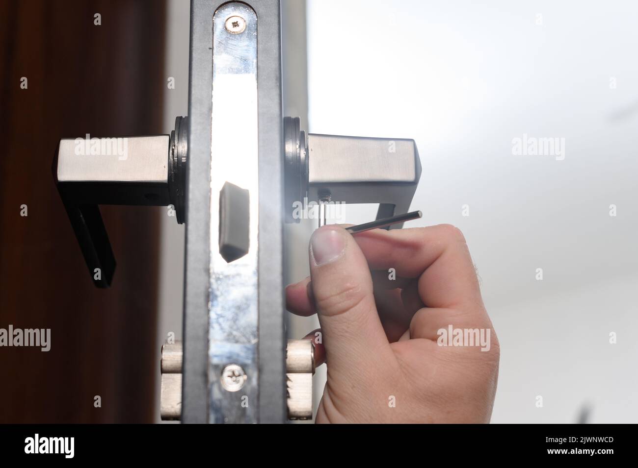 The craftsman installs the door handle with the help of a sprocket key