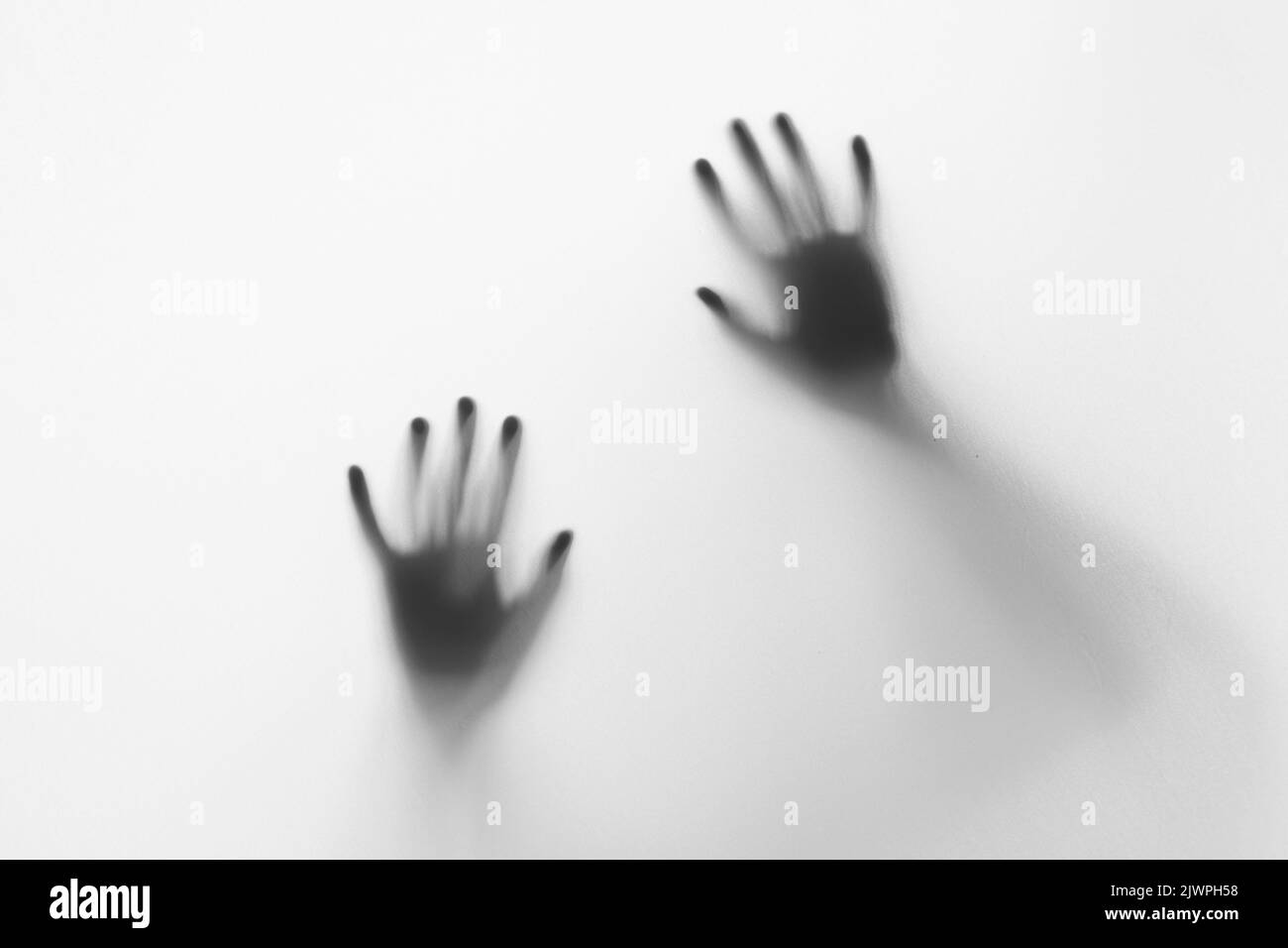 Defocused hand silhouette behind frosted glass in black and white mode