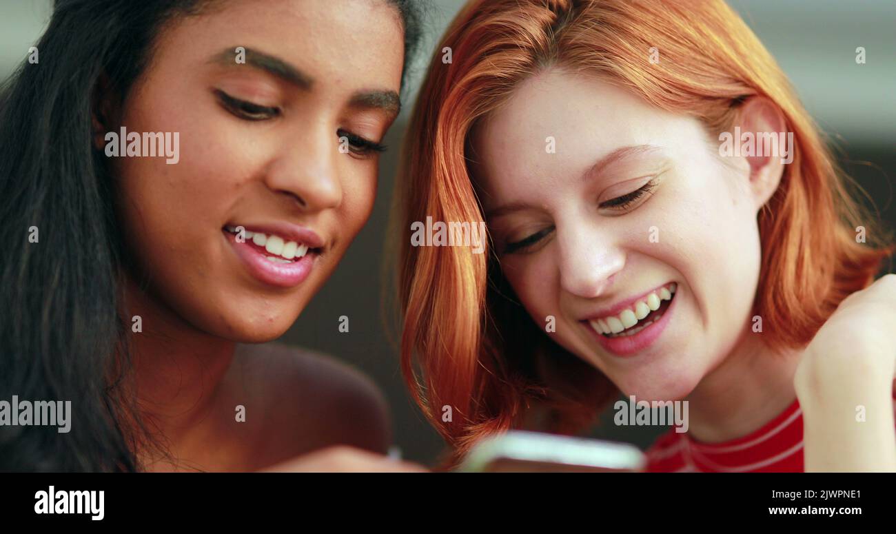 Girls looking at cellhone device screen, racially diverse Stock Photo