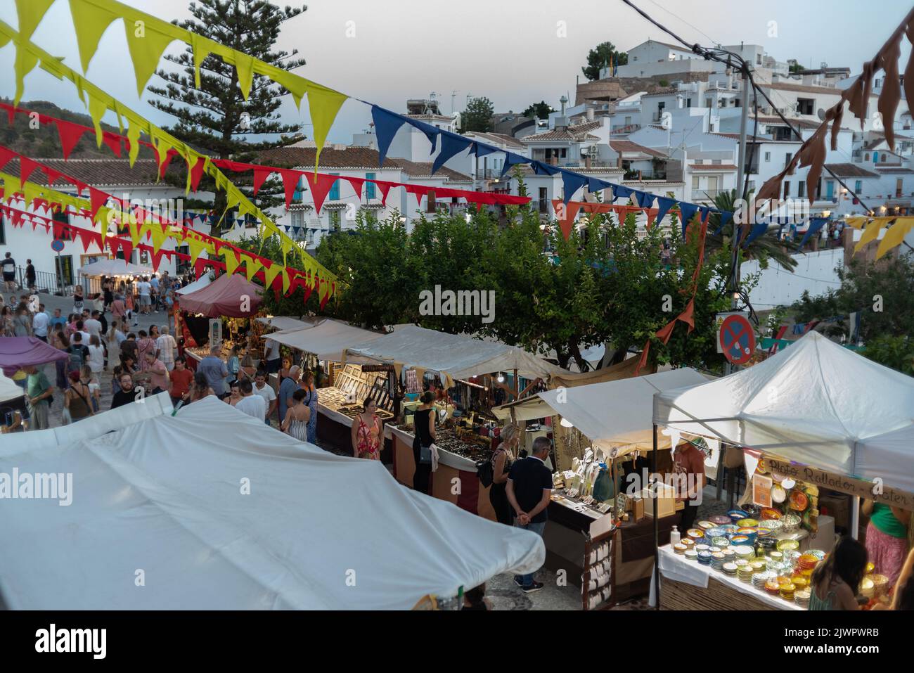 Frigiliana, Malaga, Spain, August 27, 2022: town celebrating the festival of the three cultures with garlands and people shopping at the medieval mark Stock Photo