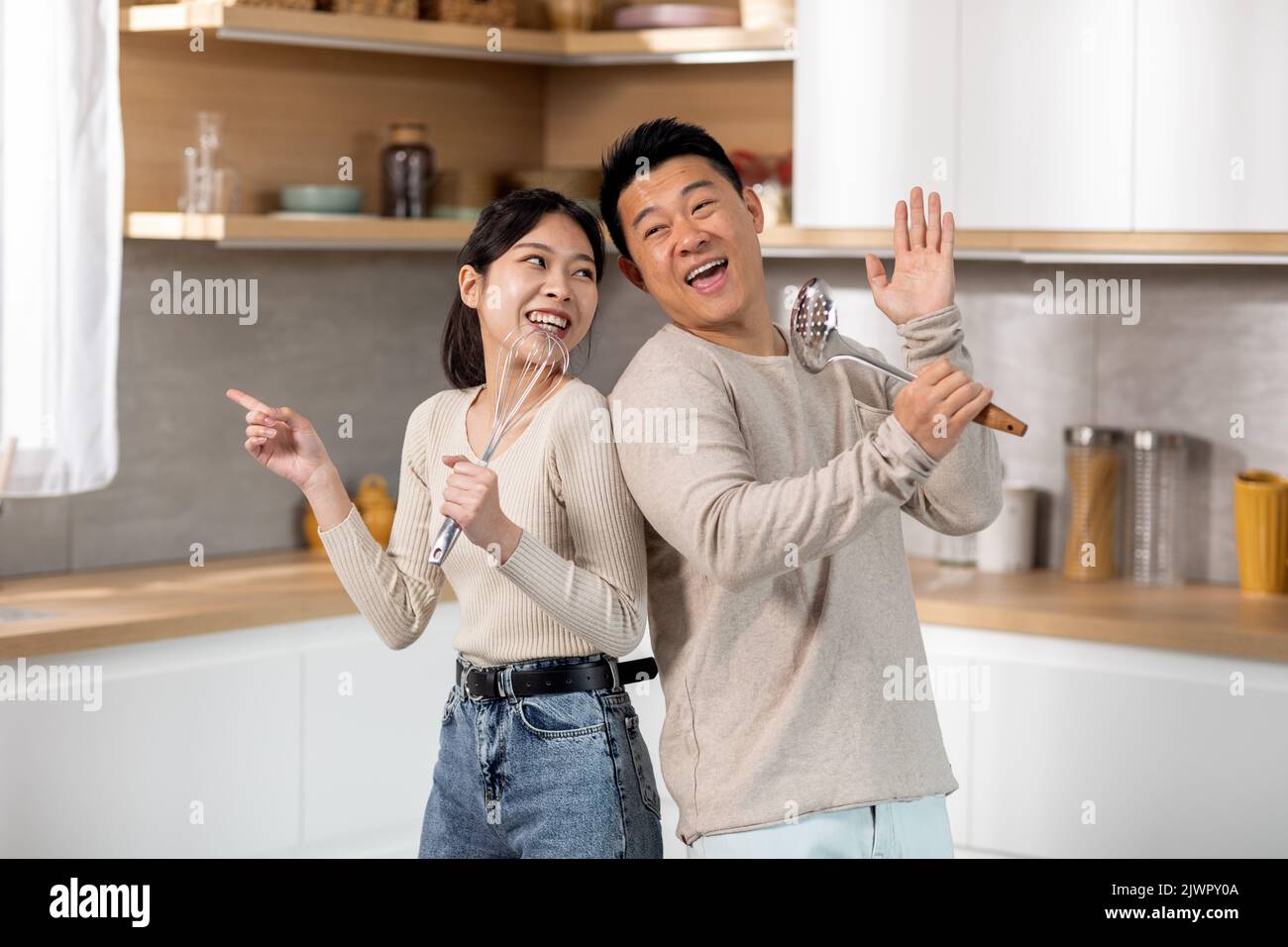 Loving asian spouses singing while cooking together Stock Photo - Alamy