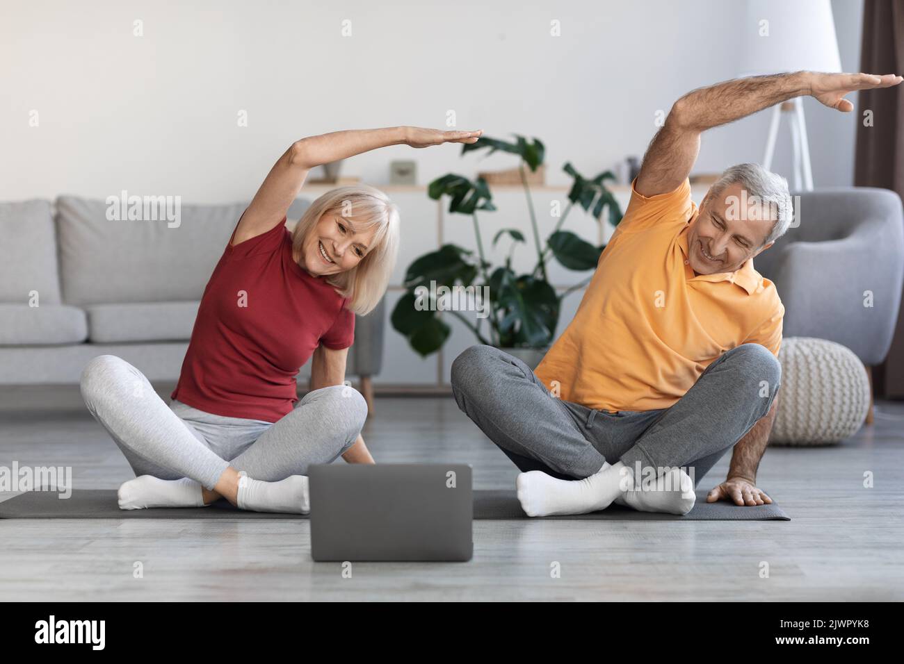 Sporty senior spouses training at home, using computer Stock Photo