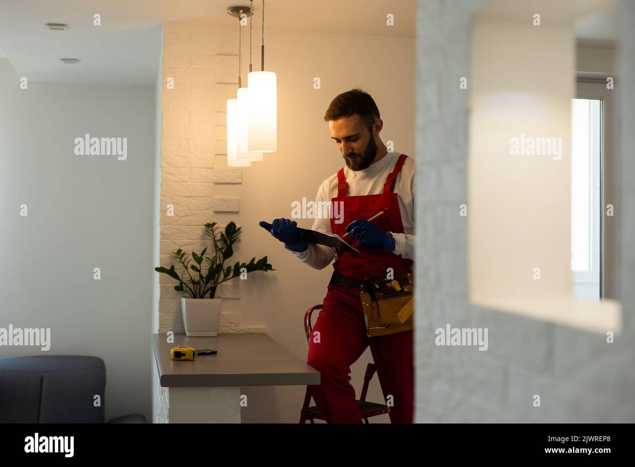 Installation lighting. Builder is holding a tablet in his hands. Concept - lighting engineer. Process installing. Electrician Stock Photo