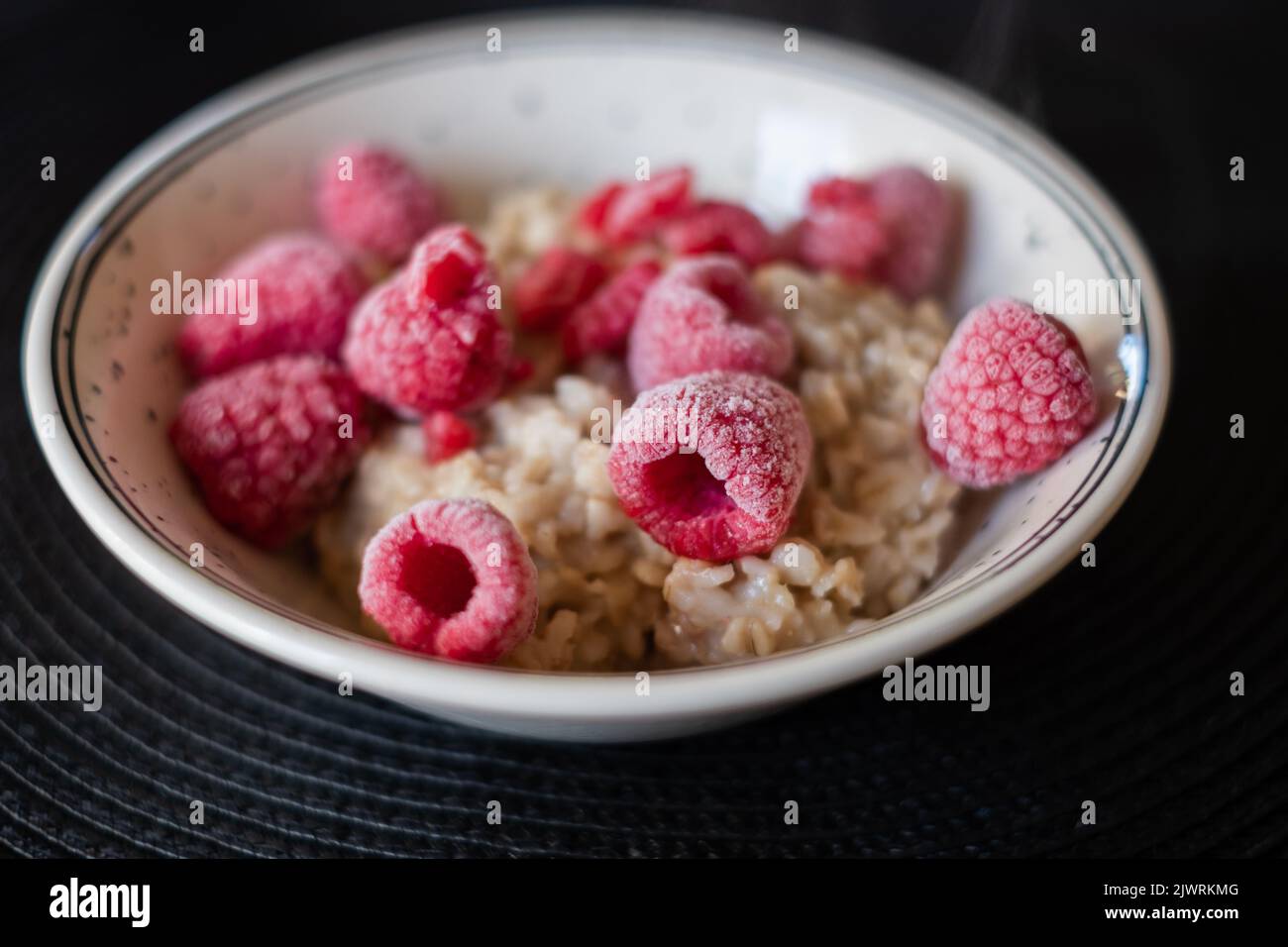 Hot oatmeal porridge with cold frozen berries steaming. Kids menu. Stock Photo