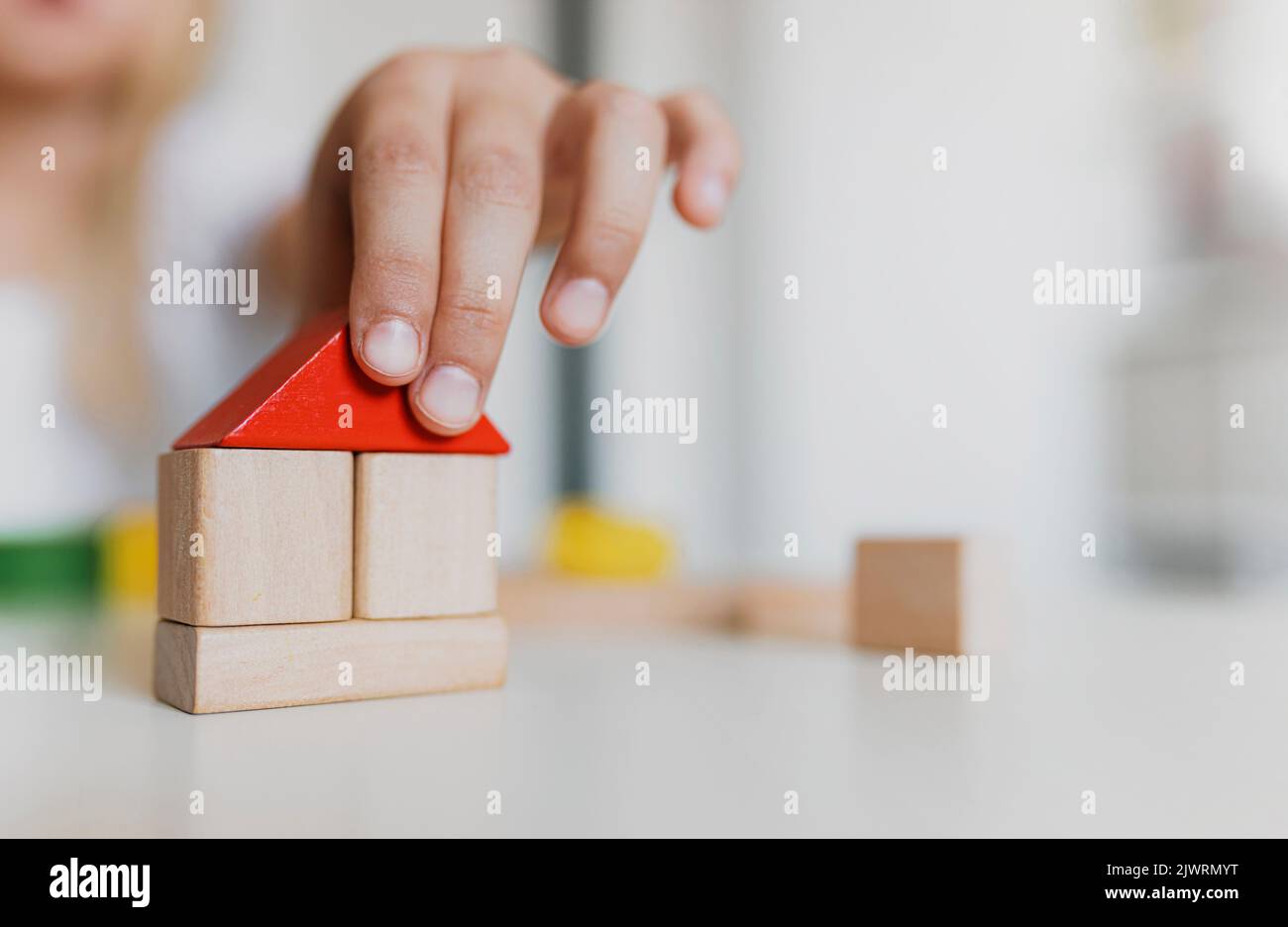 Little child girl of preschooler age playing wooden building blocks at home or kindergarten. Kid