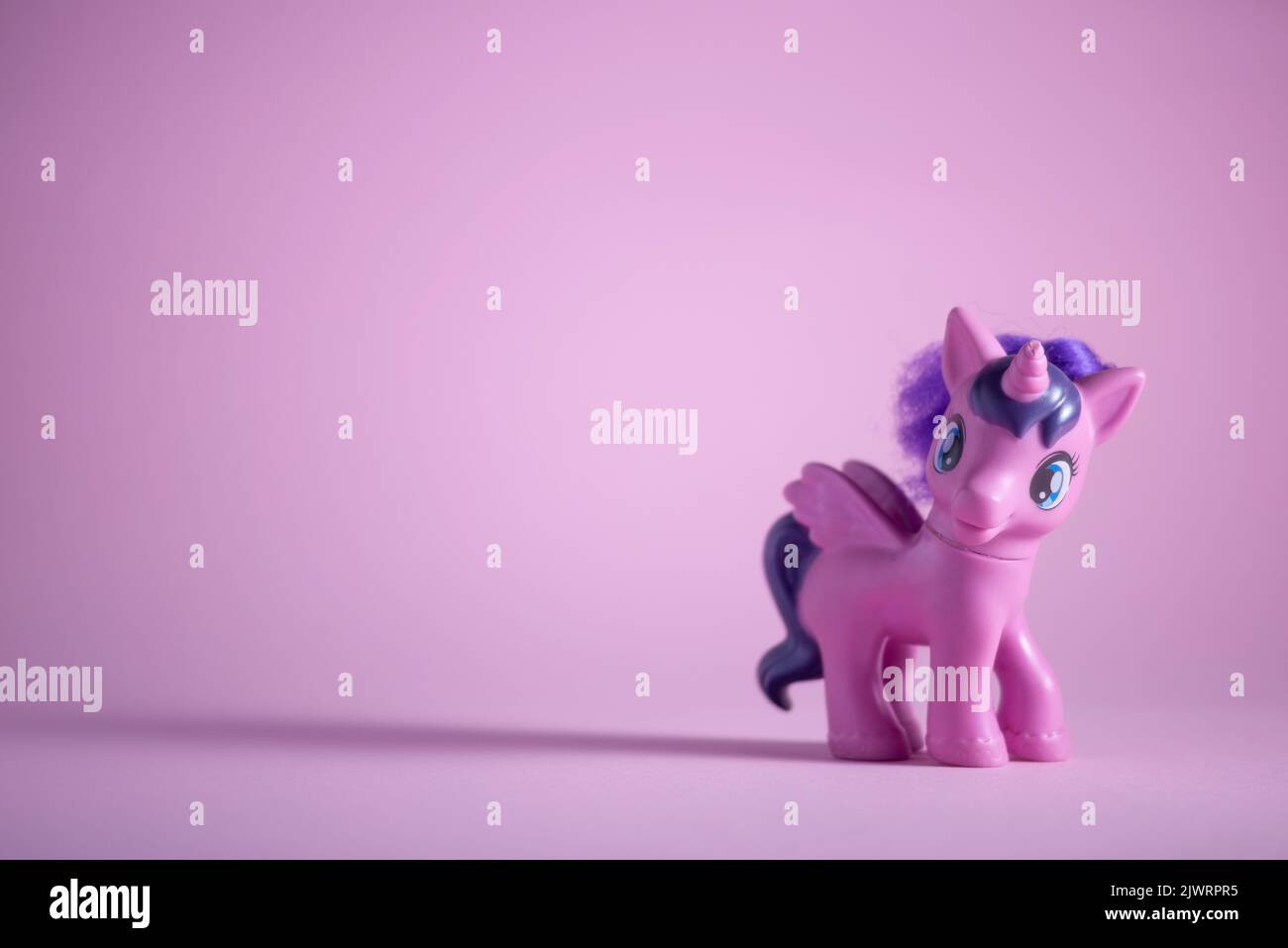 toy pink unicorn pony on a pink background. Stock Photo