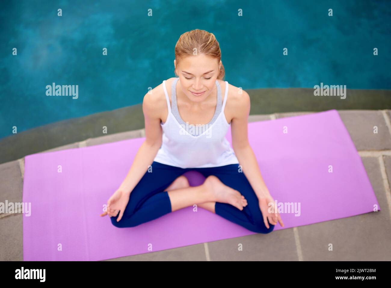 Nothing interrupts my zen time. a young woman doing yoga next to a swimming pool outside. Stock Photo