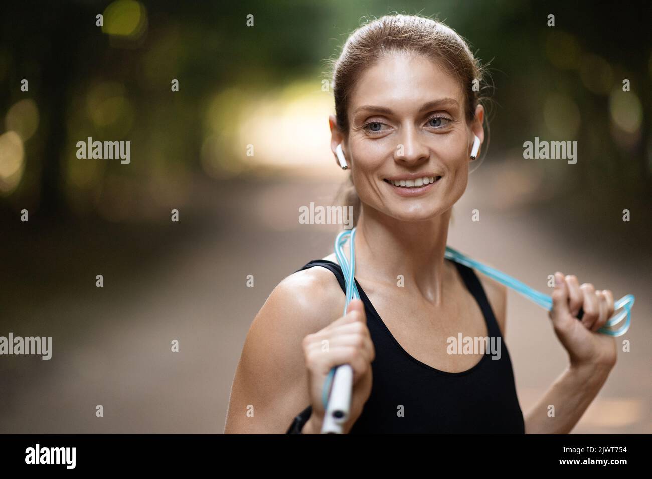 Athletic young woman doing workout outdoors, using skipping rope Stock Photo