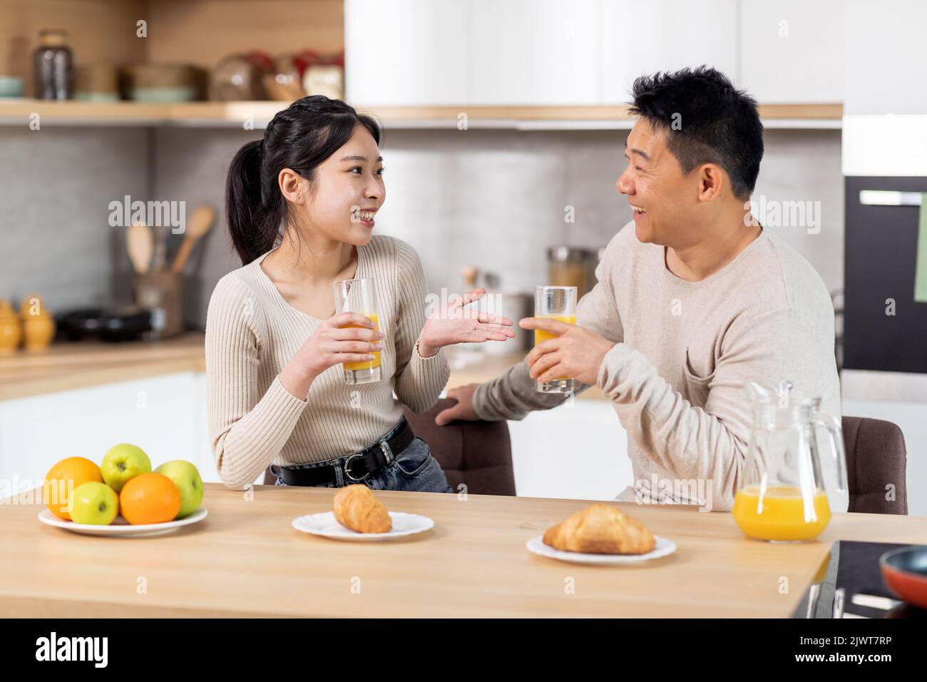 Happy asian spouses having fun while eating at kitchen Stock Photo