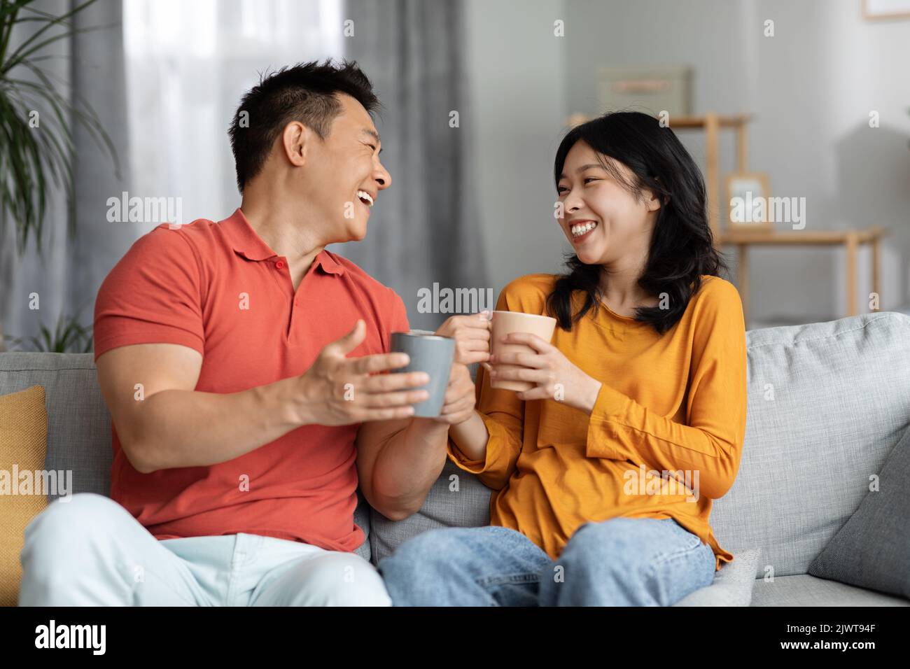 Positive korean lovers drinking tea, having conversation Stock Photo