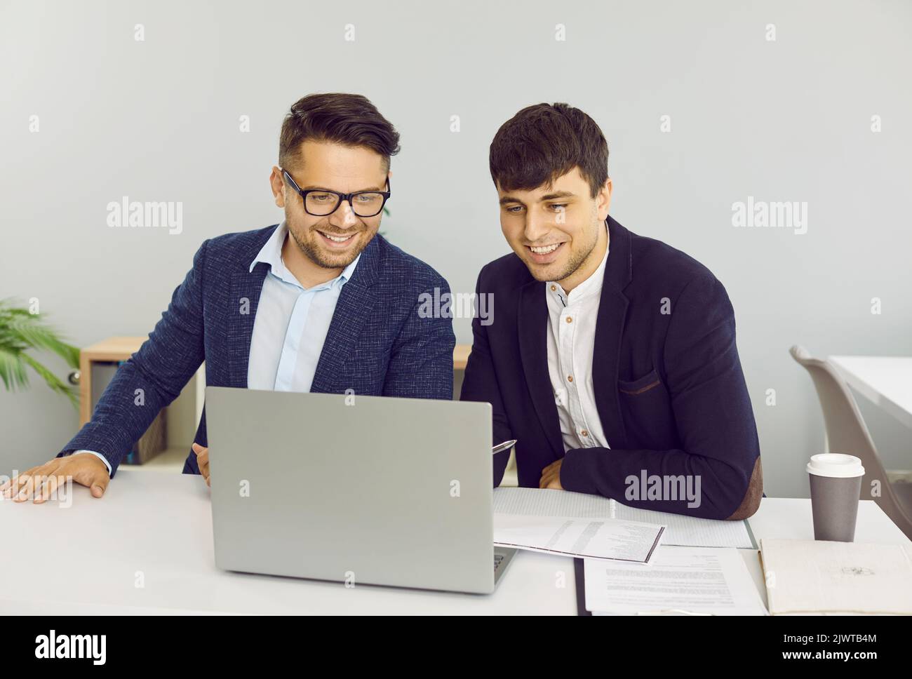 Two friendly male colleagues are working together in office on joint startup project. Stock Photo