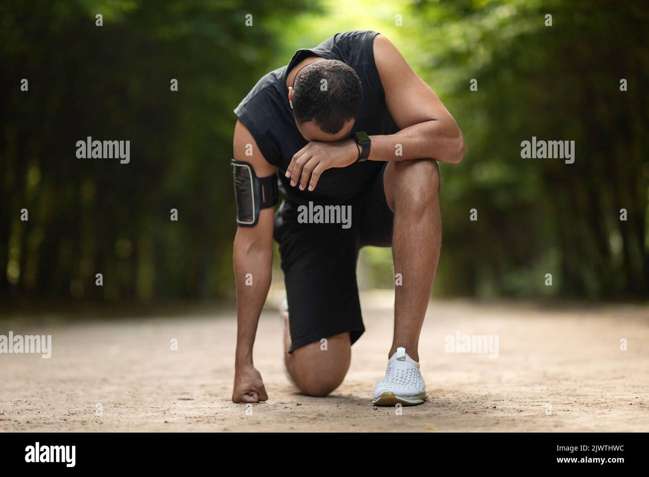Black sportsman feeling bad while jogging by park Stock Photo