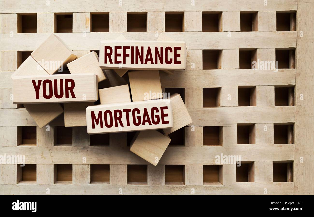 Wooden block forms the words REFINANCING YOUR MORTGAGE on a beautiful background, copy space. Stock Photo
