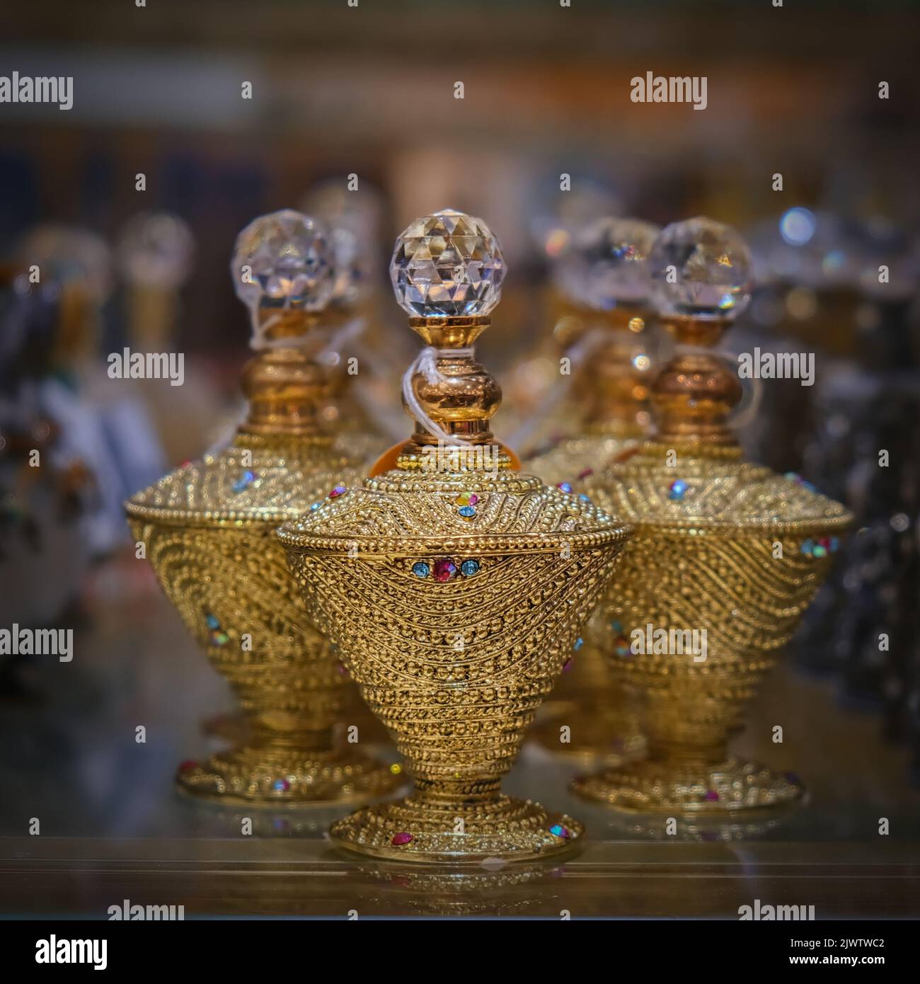 Blurred photo of Perfume Shop Display with three golden-colored ornate oriental perfume bottles for oud or aroma essence oil close up. Stock Photo