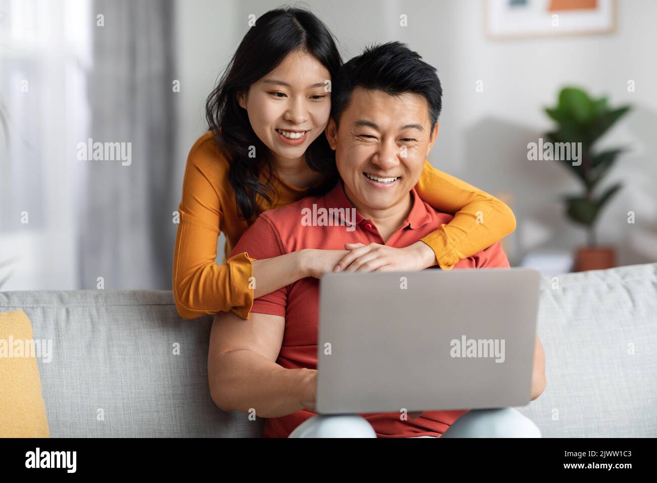 Happy korean couple using computer together at home Stock Photo