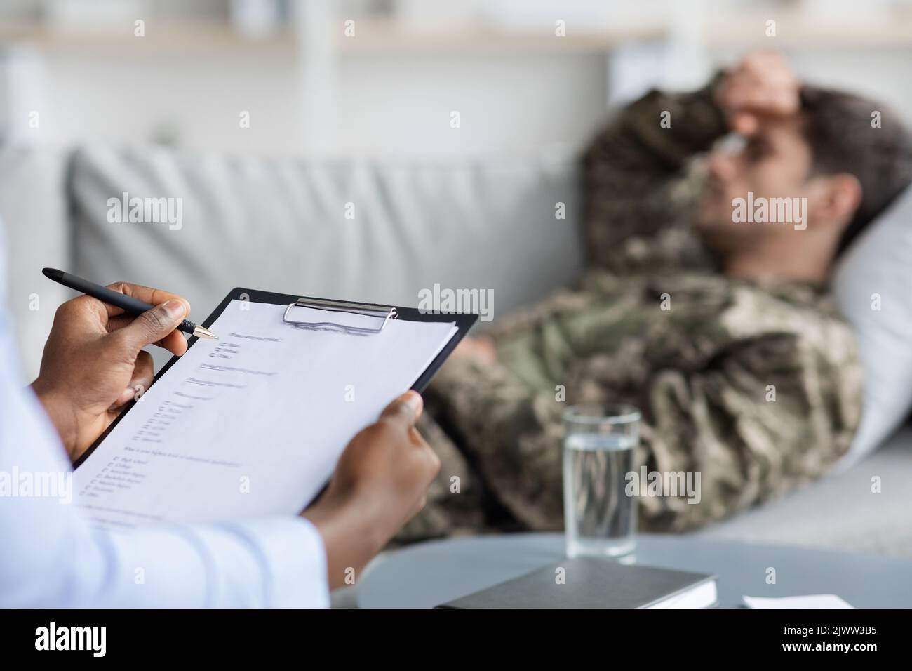 Black doctor taking notes while having conversation with veteran Stock Photo