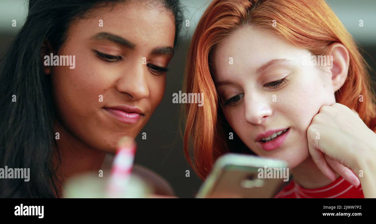 Two racially diverse girls looking at cellphone screen Stock Photo
