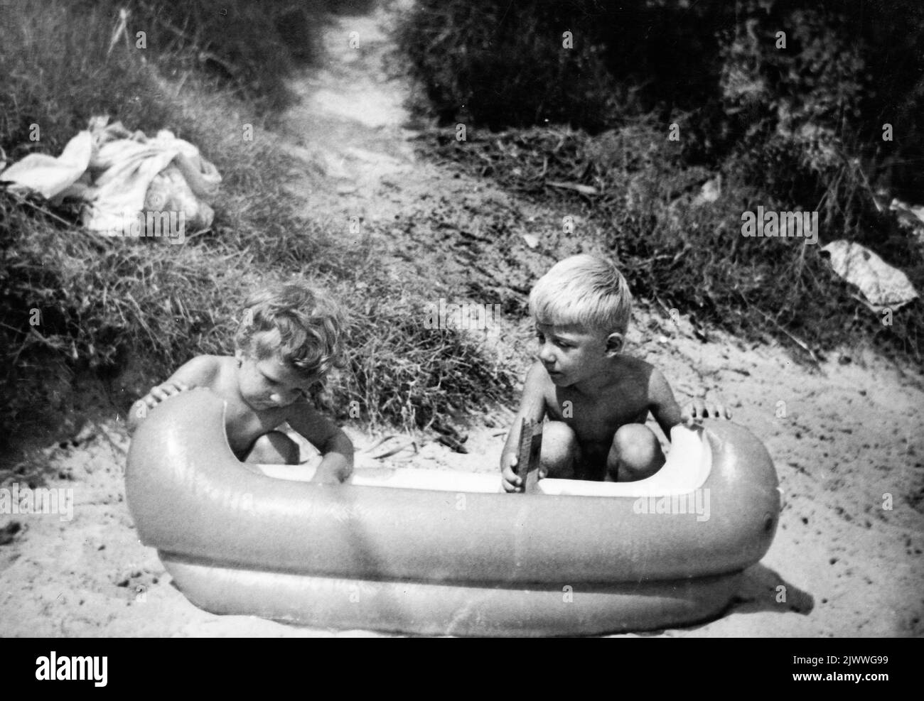 Siblings aged 2 and 4 years old playing on the beach with inflatable toy kiddy canoe Stock Photo