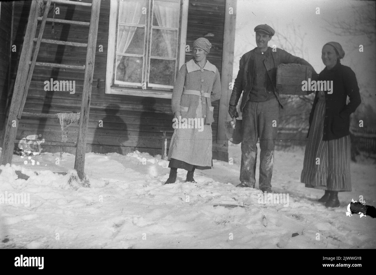 Two women, one man in front of houses. Två kvinnor, en man framför hus. Stock Photo