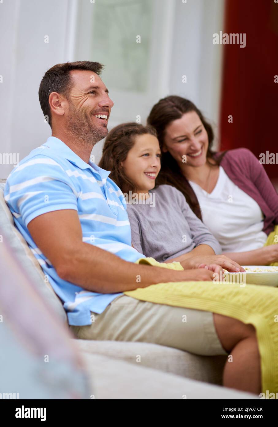 They love their comedies. a family watching a movie on the sofa. Stock Photo