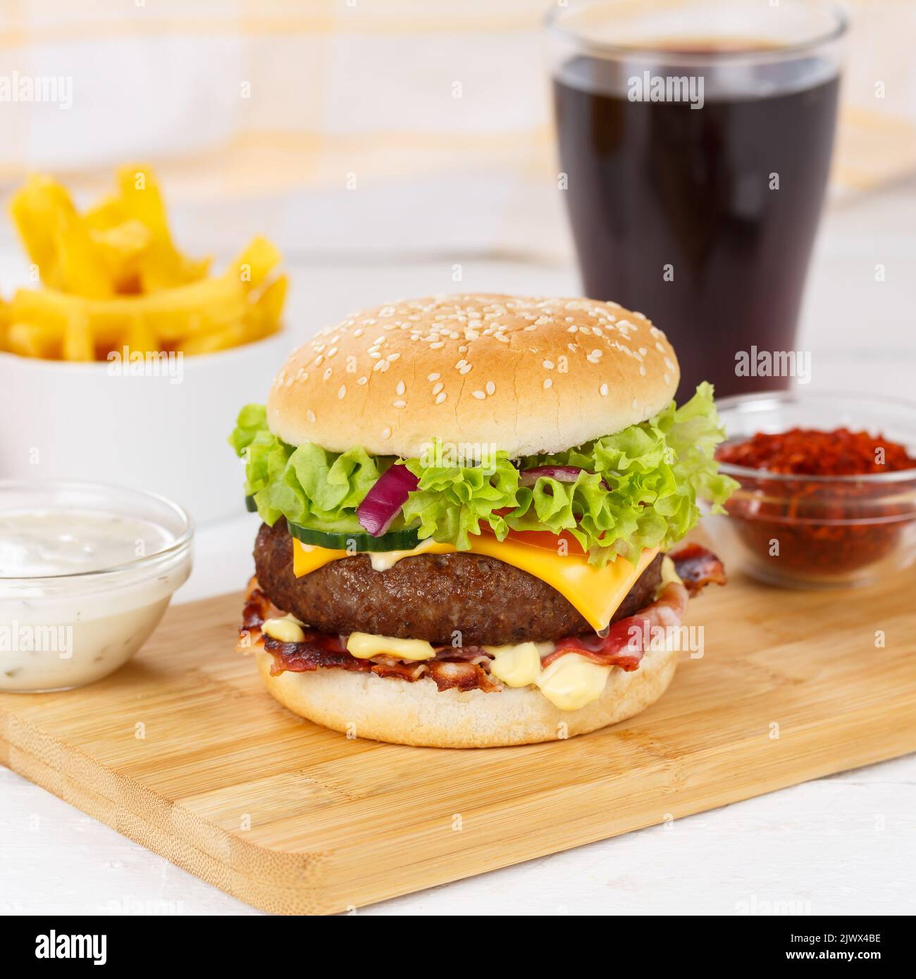 Hamburger Cheeseburger meal fastfood fast food with cola drink and French Fries on a wooden board square menu Stock Photo