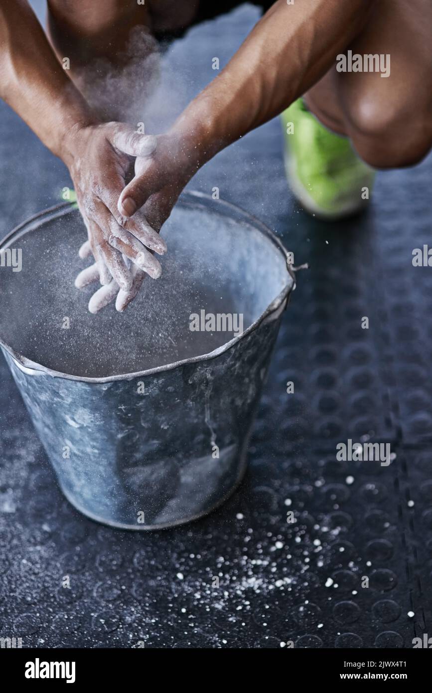 Use the chalk. a young man putting chalk powder on his hands at the gym