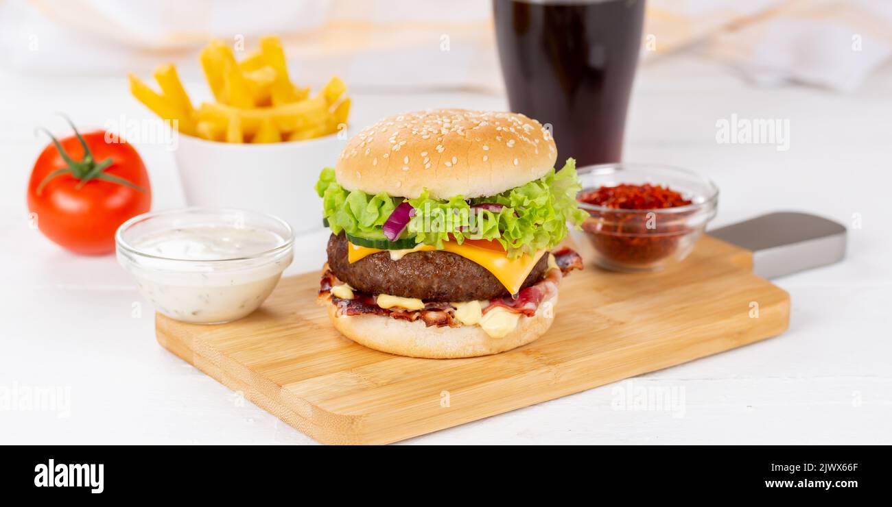 Hamburger Cheeseburger meal fastfood fast food with cola drink and French Fries on a wooden board panorama menu Stock Photo