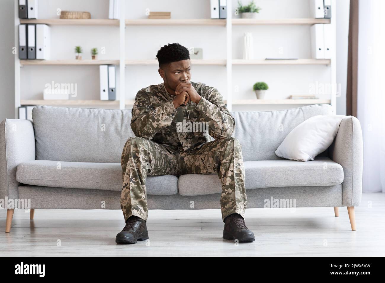 Pensive african american soldier in military uniform sitting on couch Stock Photo