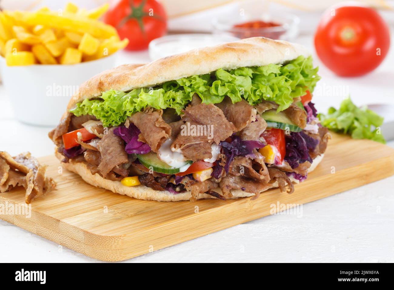 Döner Kebab Doner Kebap fast food meal in flatbread with french fries on a kitchen board Stock Photo
