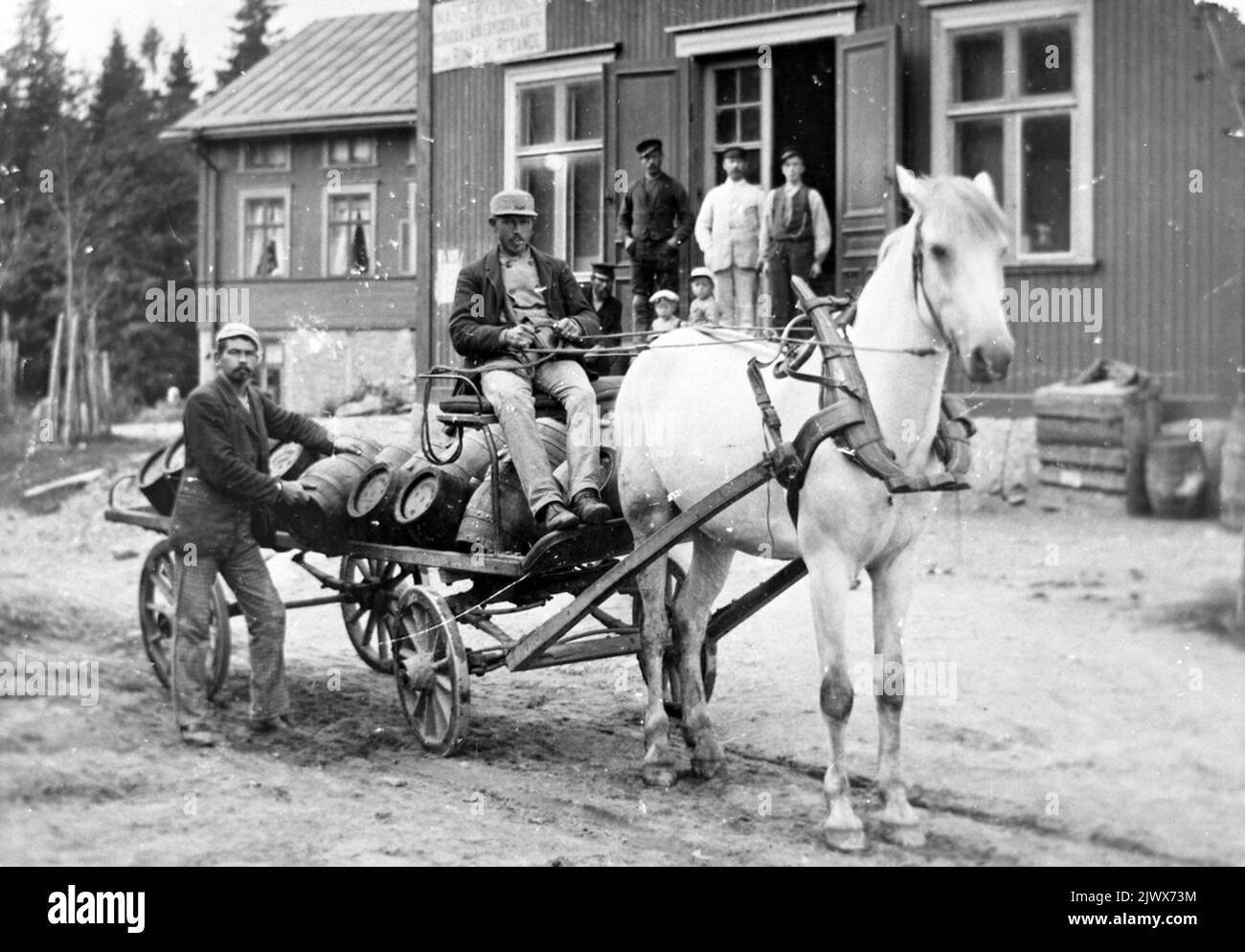 Brewery horse that delivers drinks in barrels from Wilanders Brewery at Kvistholmen. The man on the left may be Per Olof Sahlin, who was the runner at the brewery. On the facade of the house stands food service, unreadable word and room for travelers. Bryggarhäst som levererar dricka i tunnor från Wilanders bryggeri på Kvistholmen. Mannen till vänster kan vara Per Olof Sahlin, som var utkörare på bryggeriet. På husets fasad står Matservering, oläsbart ord och Rum för resande. Stock Photo