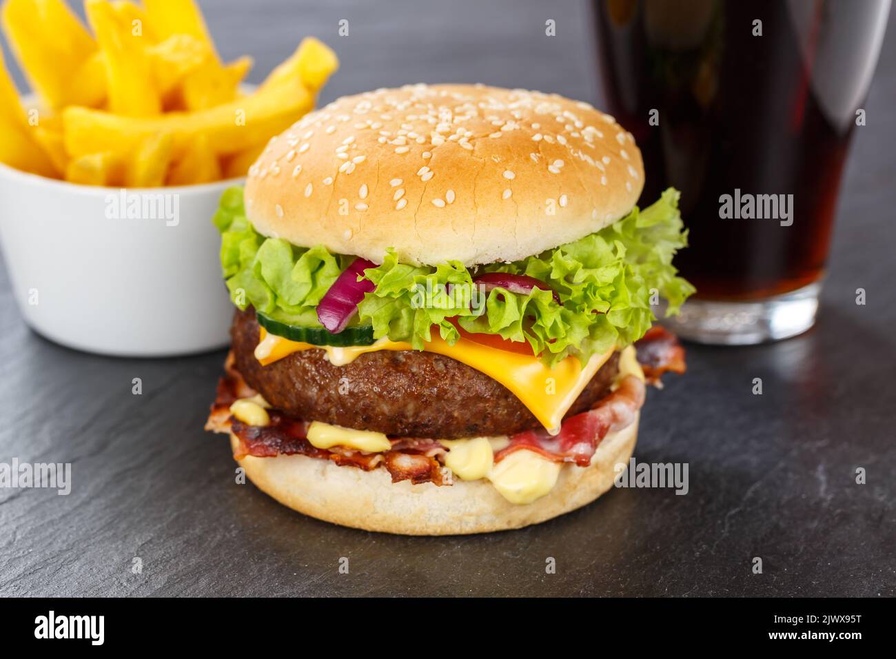 Hamburger Cheeseburger meal fastfood fast food with cola drink and French Fries on a slate menu Stock Photo