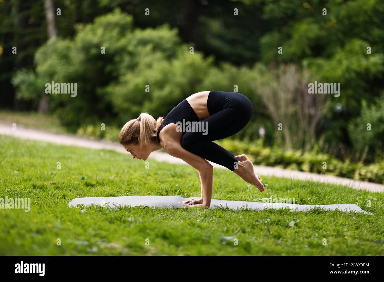 Side view of athletic woman standing in crow pose Stock Photo