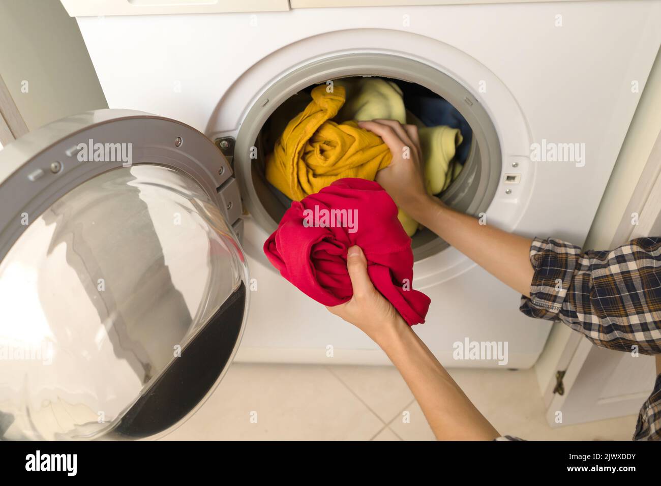 Woman puts bright clothes into a washing machine Stock Photo Alamy