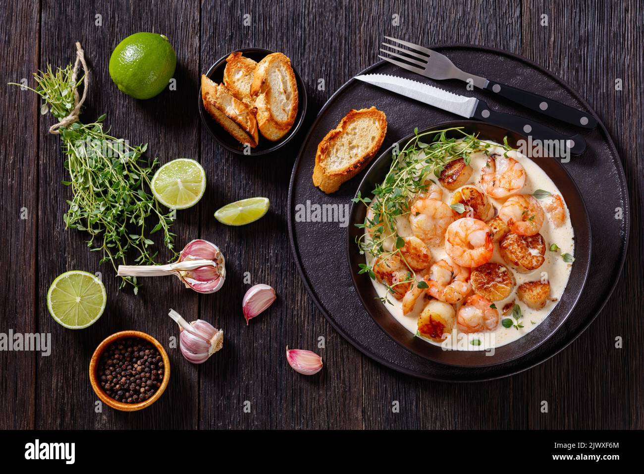shrimps and scallops in spicy coconut cream sauce in black bowl on dark