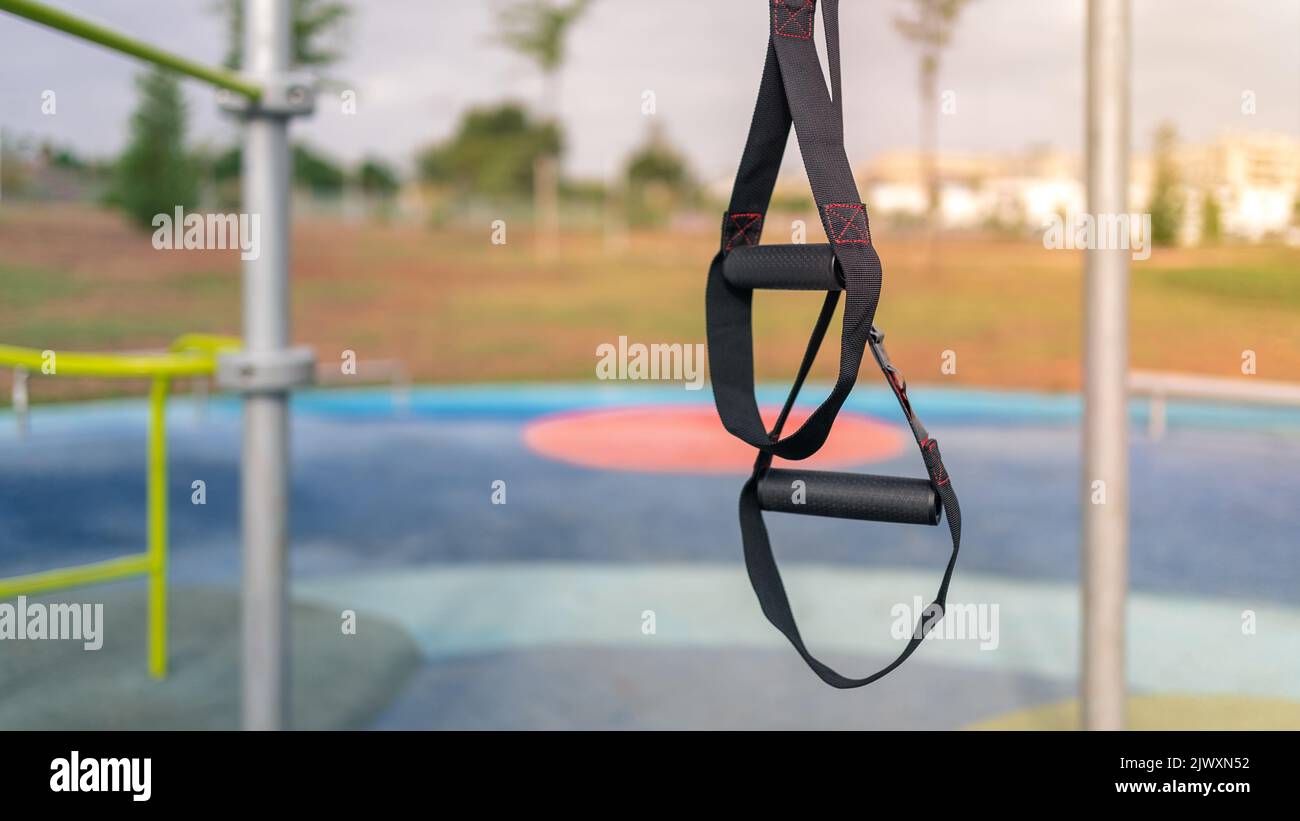 Great TRX workout fitness to exercises outdoors. A special hanging device for exercising outside in sunny city park. Healthy lifestyle concept. Stock Photo