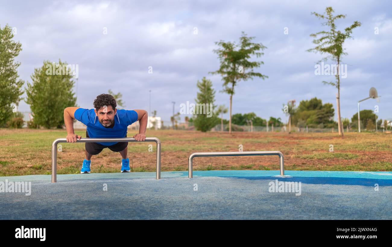 Sport man doing exercise push up. Caucasian person workout at city park. Calisthenics body building activity. Gym bodybuilder and sport excercise conc Stock Photo