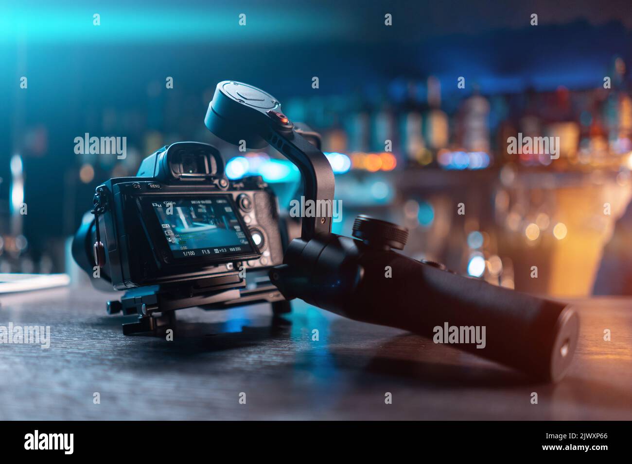 portable handheld video gimbal with mirrorless dslr camera on wooden table Stock Photo