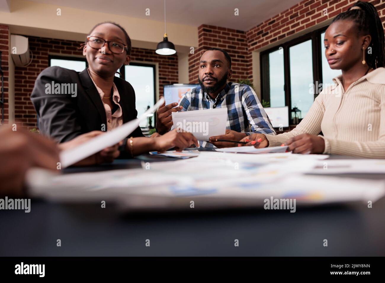 Work colleagues brainstorming ideas to create report, using company