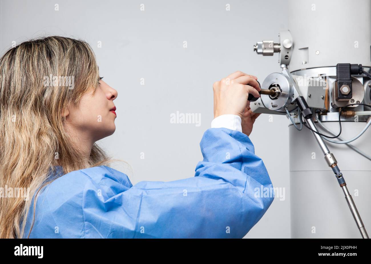 Young female scientist loading a specimen using a sample holder into a
