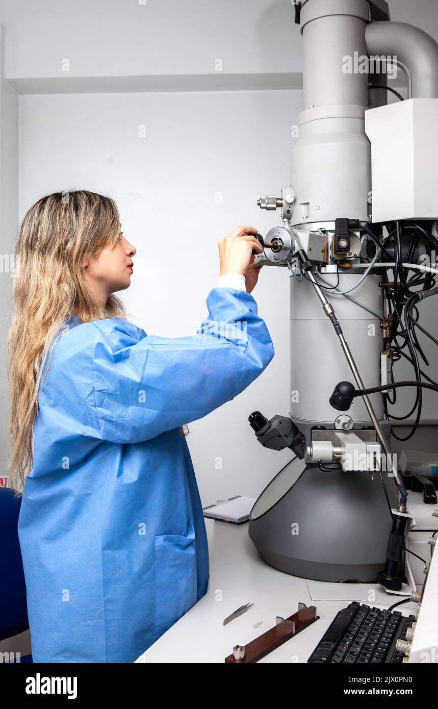 Young female scientist loading a specimen using a sample holder into a