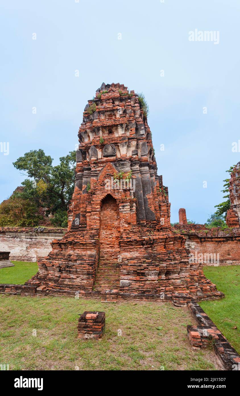 Leaning red brick prang in danger of collapse in the ruins at Wat Maha That, the sacred royal temple in Ayutthaya, Thailand Stock Photo