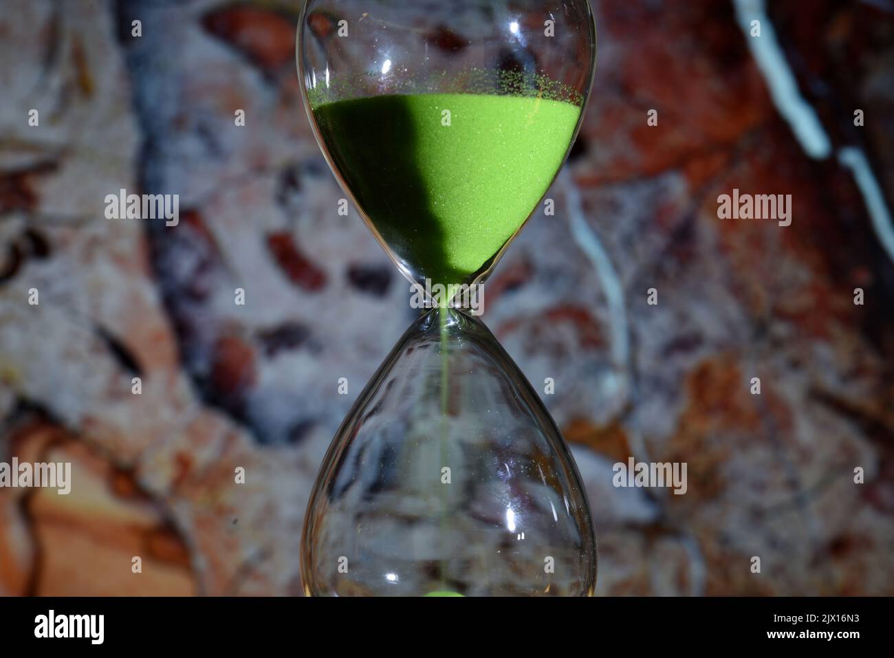Detalle de un reloj de arena de color verde, contando el tiempo, sobre diferentes fondos Stock Photo
