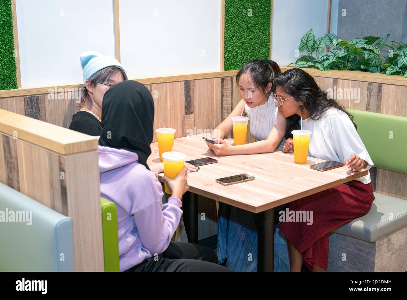 Young Asian women having a great time in a cafe. Drinking orange juice and socializing. Stock Photo