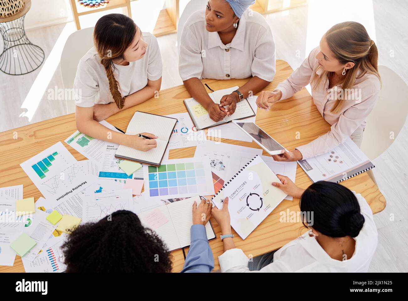 Creative team planning a project with digital tablet and paperwork in corporate office. Top view of professional employees writing notes and analyzing Stock Photo